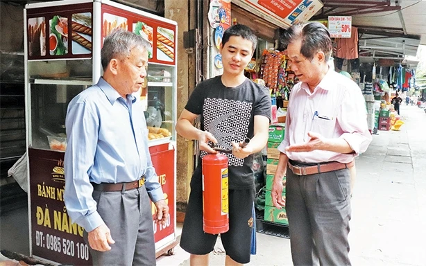 Ông Phạm Ngọc Nam (ngoài cùng bên phải) hướng dẫn người dân sử dụng bình cứu hỏa mi-ni.