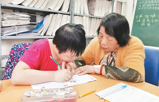 Bà giáo Nguyễn Thị Côi hướng dẫn học sinh lớp học tình thương tập viết. 
