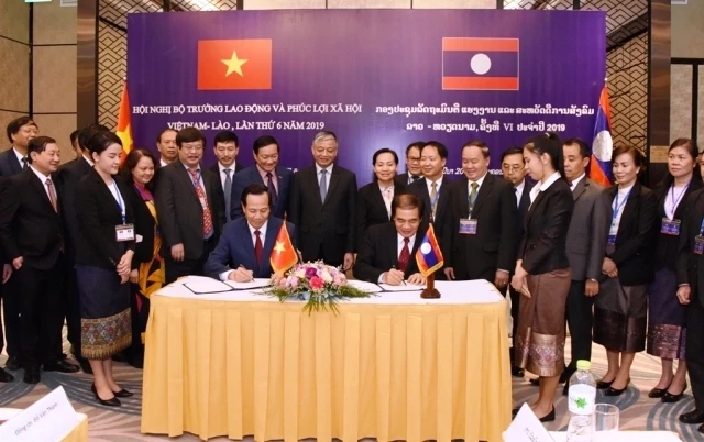 Bộ trưởng Bộ Lao động, Thương binh và Xã hội Đào Ngọc Dung (trái) và Bộ trưởng Bộ Lao động và Phúc lợi xã hội Lào Khampheng Saysompheng ký Biên bản Hội nghị, ngày 28-3.