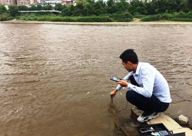 : Cán bộ Sở TNMT Lào Cai lấy mẫu nước sông Hồng để phân tích, xác định nguyên nhân cá chết hàng loạt tại đây.