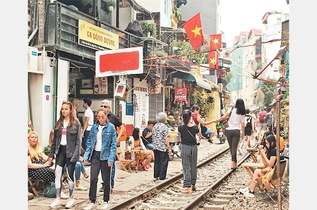 Khách du lịch chụp ảnh, uống cà-phê ngay sát đường ray tuyến đường sắt bắc - nam, đoạn qua địa bàn phường Hàng Bông.