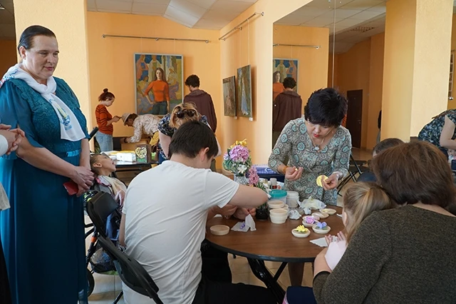 Bà Irina Umnova, Chủ tịch Quỹ quốc tế "Con đường hòa bình" và Trung tâm xã hội nhân văn "Luật hòa bình" (bên trái) đang dõi theo Nghệ nhân Việt Nam Hà Linh Hương (đứng giữa) dạy các em nhỏ làm hoa đất