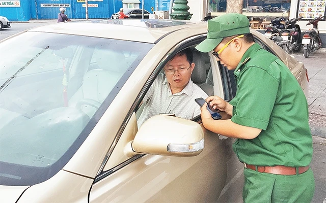 Lực lượng Thanh niên xung phong thành phố hướng dẫn chủ phương tiện cài đặt phần mềm và thanh toán phí đậu xe ô-tô qua điện thoại thông minh tại tuyến đường Phan Chu Trinh.