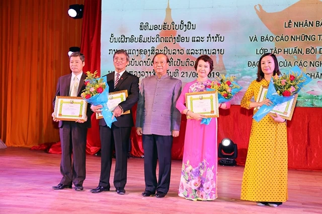 Bộ trưởng Thông tin, Văn hóa và Du lịch Lào Bosengkham Vongdara (giữa) trao giấy khen tặng các giảng viên Việt Nam và đại diện Trung tâm Văn hóa Việt Nam tại Lào, tối 21-6.