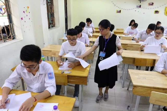 Cán bộ coi thi phát giấy làm bài cho thí sinh tại điểm thi Trường THCS Hoàng Văn Thụ (Hà Nội)