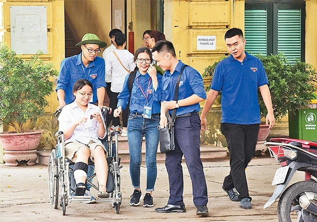 Các tình nguyện viên Quận đoàn Hoàn Kiếm hỗ trợ thí sinh bị chấn thương chân lên phòng thi.