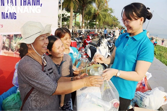 Phụ nữ quận Thanh Khê (TP Đà Nẵng) tham gia đổi rác thải nhựa lấy bình đựng nước bằng thủy tinh. Ảnh: THANH BÌNH