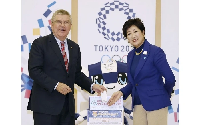 Chủ tịch Ủy ban Olympic quốc tế Thomas Bach (trái) thả một chiếc điện thoại di động cũ vào thùng quyên góp cho dự án tái chế huy chương Olympic 2020 dưới sự chứng kiến của Thống đốc Tokyo, bà Yuriko K