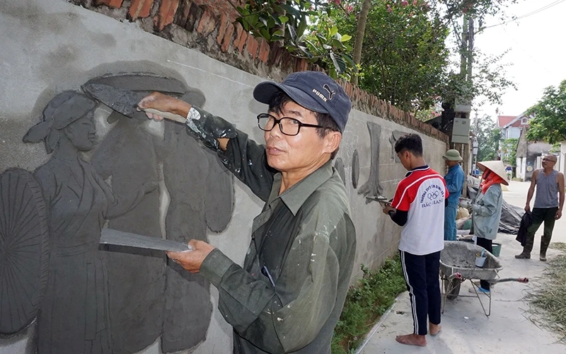 Ông Bùi Thanh Quang làm tranh đắp nổi tại làng Ðông Thượng (huyện Yên Dũng), chung tay vì nông thôn sạch đẹp.