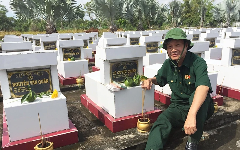 Cựu chiến binh Trần Tường Huấn bên mộ các đồng đội (Trung đoàn 59, Bộ Tư lệnh Thủ đô) hy sinh trong trận đánh phân chi khu Vĩnh Xuân, tại Nghĩa trang Liệt sĩ huyện Trà Ôn, tỉnh Vĩnh Long.