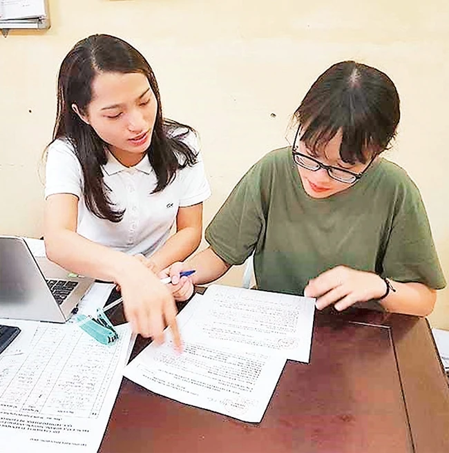 Giáo viên Trường THPT Phạm Hồng Thái hướng dẫn thí sinh thực hiện thay đổi nguyện vọng bằng phiếu. Ảnh: MAI HIỀN