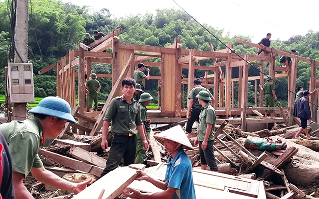 Lực lượng công an giúp hộ dân cụm bản Sa Ná tháo dỡ cấu kiện nhà sàn để dựng lại nhà tại nơi ở mới.