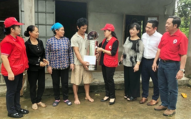 Ðại diện Hội Chữ thập đỏ Việt Nam trao tiền và quà hỗ trợ người dân bị thiệt hại do mưa lũ ở tỉnh Ðồng Nai. Ảnh: HỒNG HẠNH