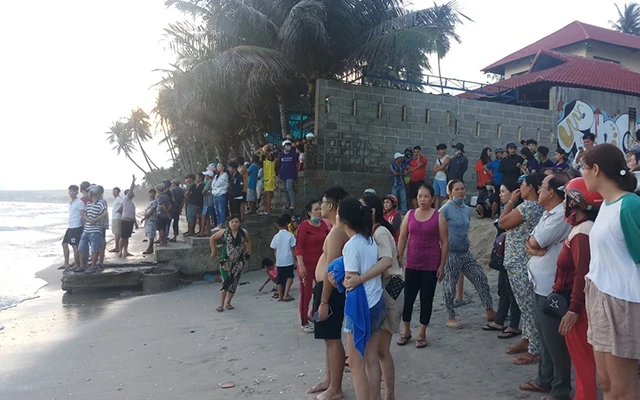 Nhiều du khách và người dân địa phương tập trung tại bờ biển trông ngóng, tìm kiếm bốn thanh niên bị sóng biển cuốn.