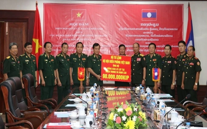 Trung tướng Hoàng Xuân Chiến (bên trái) trao 90 triệu kíp Lào nhằm hỗ trợ người dân Lào khắc phục hậu quả lũ lụt.