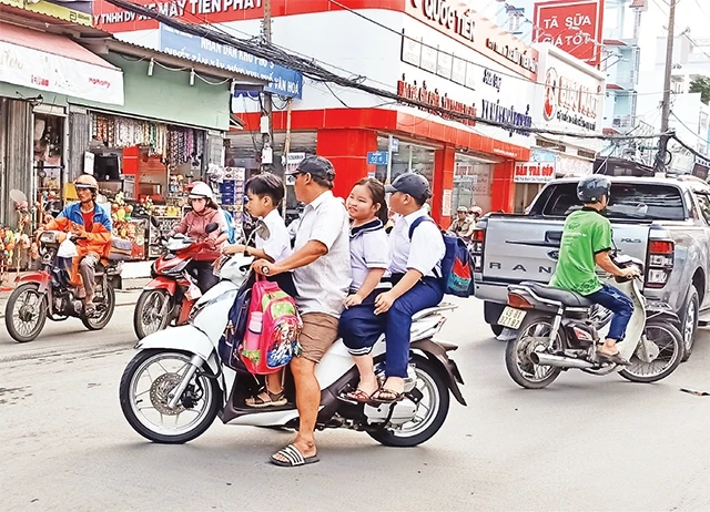 Nhiều bậc cha mẹ chưa quan tâm việc đội nón bảo hiểm cho học sinh. (Ảnh chụp tại đường Nguyễn Duy Trinh, quận 2).