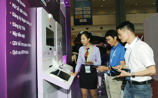 Nhân viên Ngân hàng Tienphong Bank giới thiệu các dịch vụ công nghệ số cho khách tham quan tại Diễn đàn kinh tế tư nhân Việt Nam 2019. Ảnh: QUANG MINH
