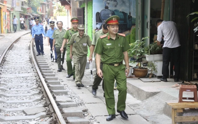 Lực lượng chức năng kiểm tra, nhắc nhở các cửa hàng kinh doanh tại khu vực đường tàu phố Phùng Hưng. (Ảnh: ĐĂNG ANH)