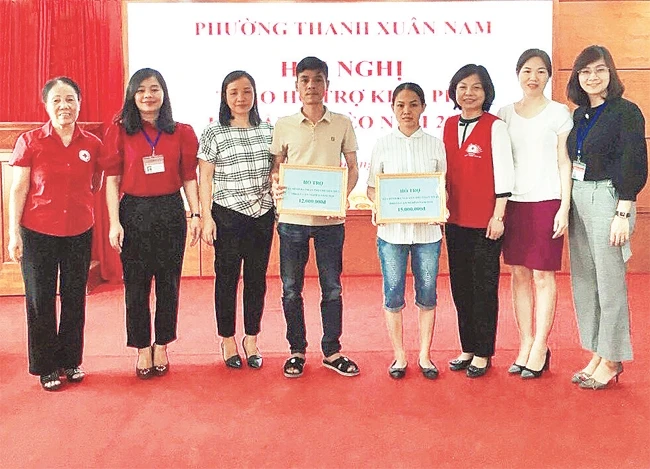 Đại diện UBND phường Thanh Xuân Nam, quận Thanh Xuân trao kinh phí hỗ trợ các gia đình thoát cận nghèo năm 2019. Ảnh: THU TRANG