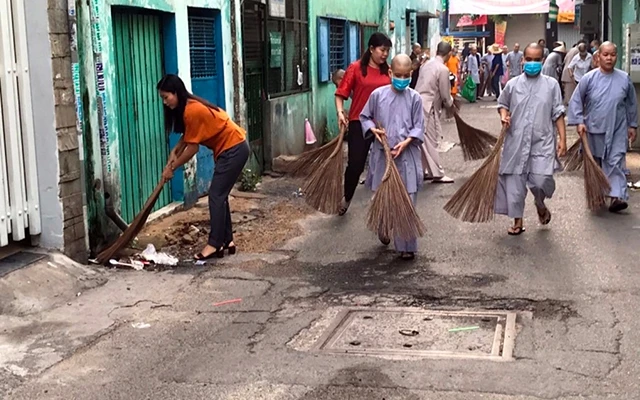 Tăng, ni, phật tử chùa Bồ Ðề Lan (quận 6, TP Hồ Chí Minh) tham gia dọn vệ sinh môi trường, làm sạch đường phố tại khu vực phường 8. Ảnh: HUỆ LIÊN