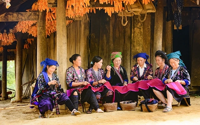 Chị Giàng Thị Mảy (ngồi giữa) cùng các thành viên tổ thêu thực hiện mẫu thêu mới.