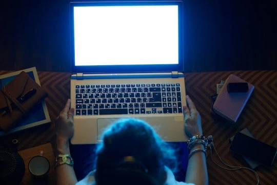 Người phụ nữ nhìn vào ánh sáng màu xanh từ màn hình máy tính. 