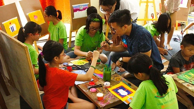 Họa sĩ Kim Duẩn hướng dẫn các em nhỏ vẽ tranh.