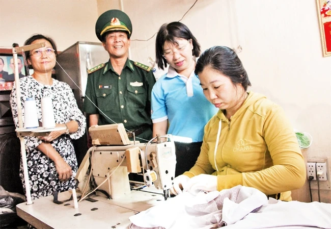 Chị Nguyễn Thị Hoa (áo vàng) bên chiếc máy may được các đơn vị trao tặng làm phương tiện sinh kế.