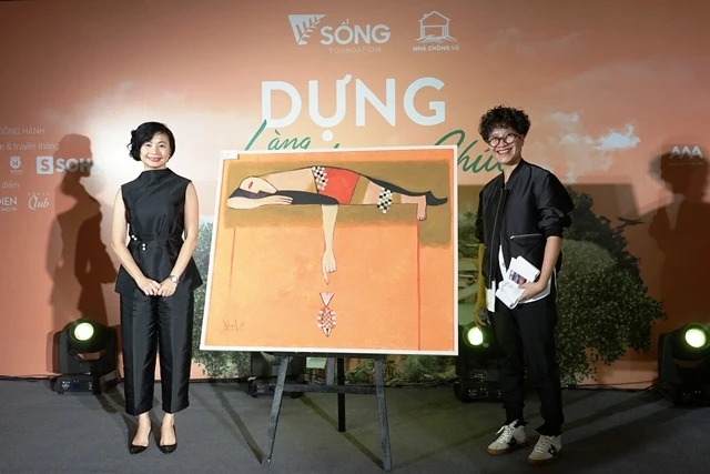 Chị Phạm Thị Hương Giang (phải) bên bức tranh được bán đấu giá tại Hà Nội.