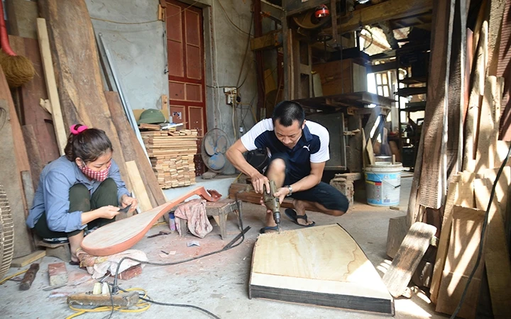 Phạm Xuân Anh và vợ anh là chị Bùi Thị Dung chế tác một cây đàn mới.
