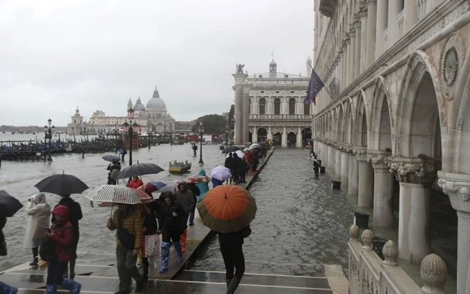 Người dân đi bộ trên lối đi được thiết kế để sử dụng trong trường hợp mực nước tại Venice dâng cao. (Ảnh: AP)