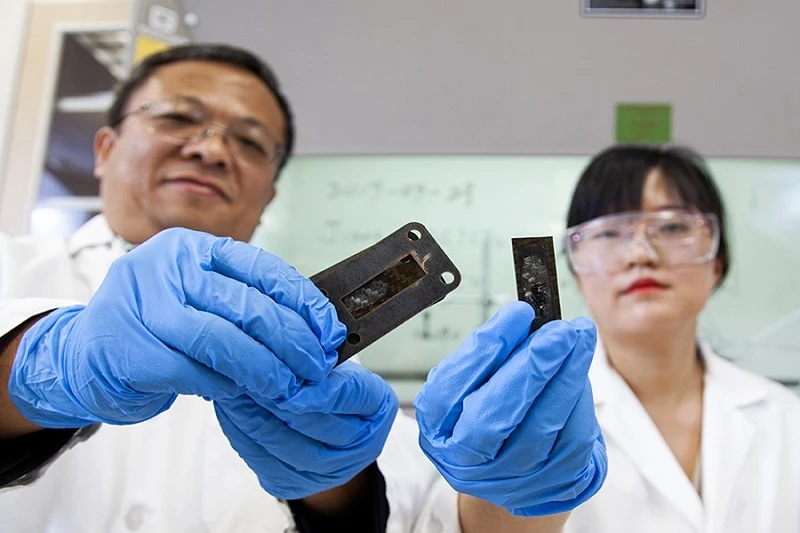 Giáo sư Richard Liang và thành viên nghiên cứu Ayou Hao cầm những mảnh vật liệu làm tấm chắn mà họ nghiên cứu đã được thử thách bằng cách nung nóng đến nhiệt độ 1.900 độ C.