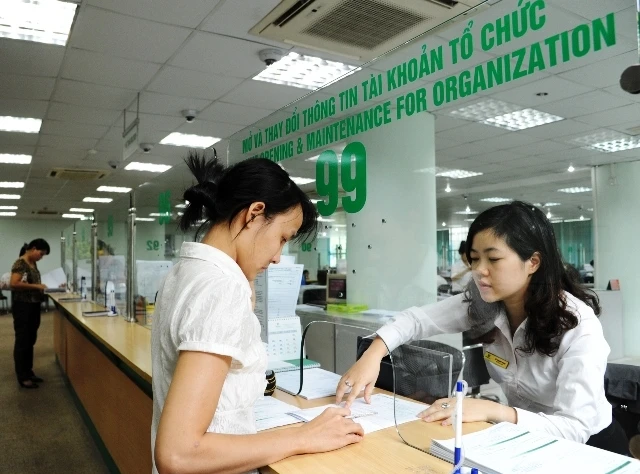 Khách hàng giao dịch tại chi nhánh ngân hàng Vietcombank. (Ảnh: KHÁNH AN)