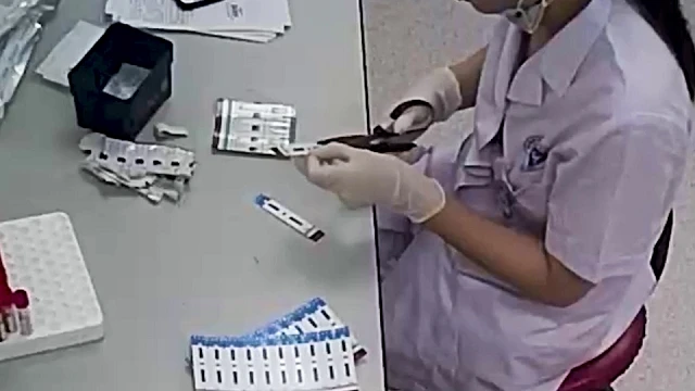 Nhân viên y tế đang cắt que thử xét nghiệm. 