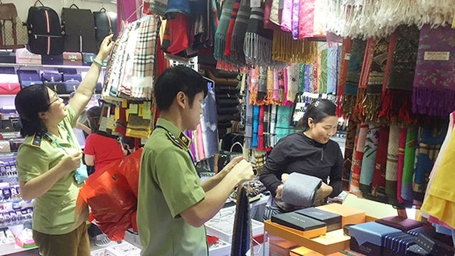 Lực lượng quản lý thị trường kiểm tra hàng giả, hàng nhái tại Trung tâm thương mại Sài Gòn Square. Ảnh: NGUYỄN HẢI