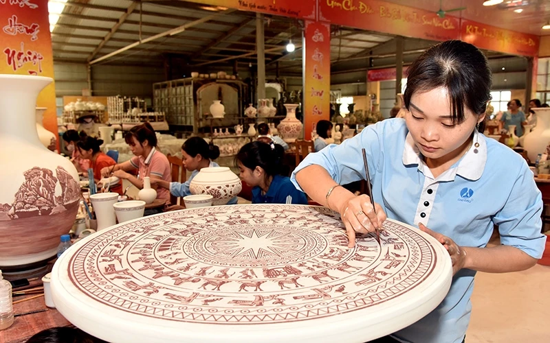 Công nhân Công ty cổ phần gốm Chu Ðậu vẽ hoa văn trên sản phẩm gốm.