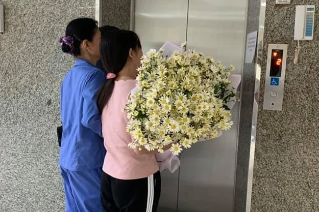 Người mẹ ôm bó hoa trắng để đón đứa con trai bé bỏng của mình trở về nhà. 