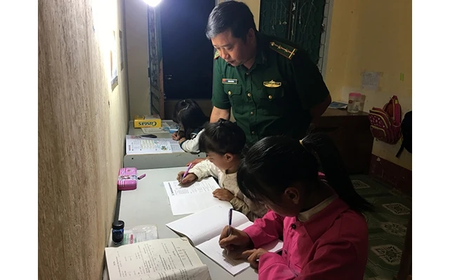 Cán bộ Ðồn Biên phòng Phó Bảng (Bộ đội Biên phòng tỉnh Hà Giang) hướng dẫn các cháu là con nuôi của đơn vị học bài.
