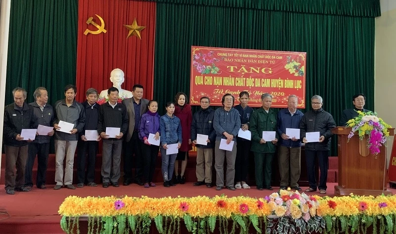 Nhà báo Nguyễn Ngọc Thanh, Trưởng Ban Nhân Dân điện tử, Báo Nhân Dân trao các phần quà cho nạn nhân chất độc da cam.