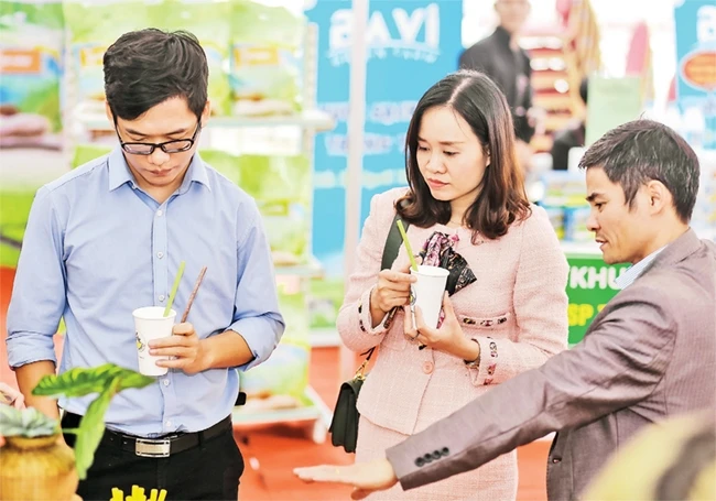 Anh Hà Văn Tám (ngoài cùng bên phải) giới thiệu sản phẩm ống hút bằng rau, củ, quả với khách hàng.