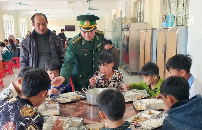 Cán bộ Đồn Biên phòng Quảng Đức quan tâm đến từng bữa ăn của các cháu tại Trường PTDT bán trú - THCS Quảng Đức, huyện Hải Hà.