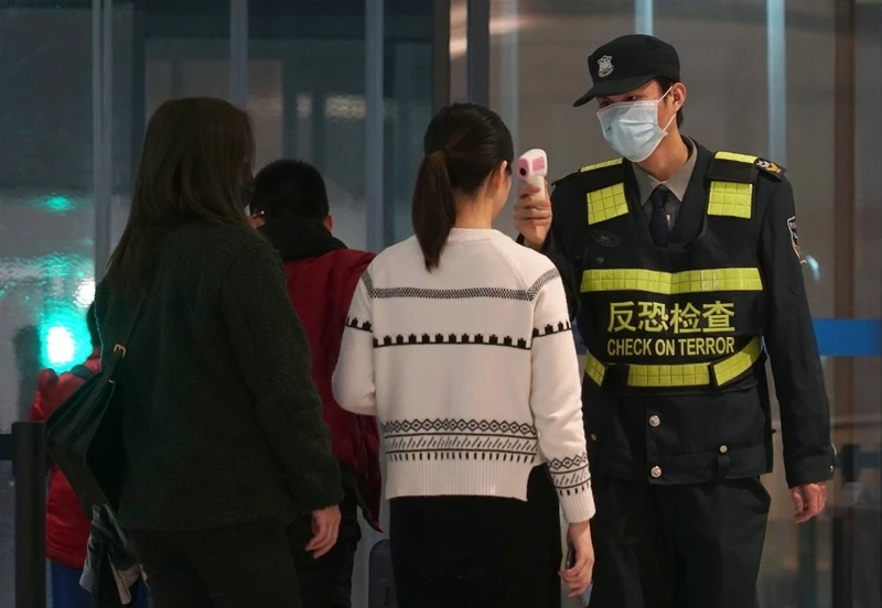 Nhân viên an ninh kiểm tra thân nhiệt của hành khách tại sân bay quốc tế ở Vũ Hán, Trung Quốc (Ảnh: AP)
