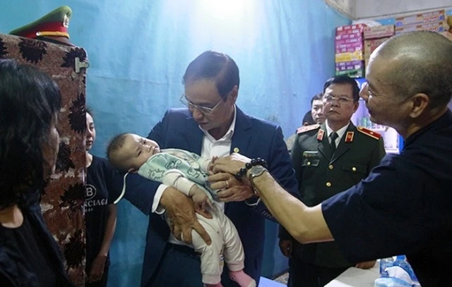 Phó Bí thư Thành ủy Hà Nội, Đào Đức Toàn bế cháu bé sáu tháng tuổi, con của liệt sĩ Phạm Công Huy. 