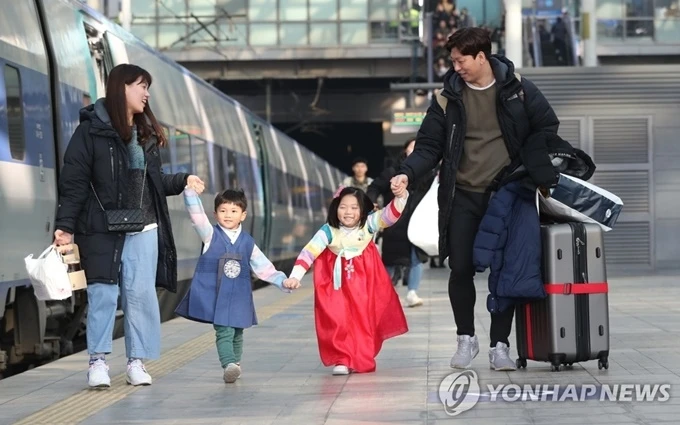 Hai em bé Hàn Quốc mặc trang phục truyền thống có mặt tại Nhà ga Seoul cùng gia đình để lên tàu về quê đón Tết. (Ảnh: Yonhap)