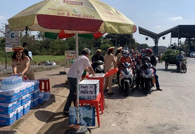CSGT Công an tỉnh Đồng Nai tặng nước uống, khăn lạnh cho người dân trở lại làm việc sau Tết trên Quốc lộ 1A.