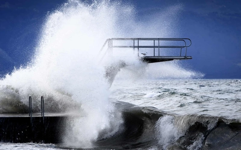 Sóng đánh vào cầu nhảy bên bờ Hồ Geneva tại Lutry, Thụy Sĩ. (Ảnh: EPA)