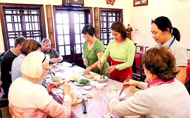 Nghệ nhân ẩm thực Ánh Tuyết (người đeo kính) hướng dẫn khách du lịch nước ngoài làm món nộm đu đủ.