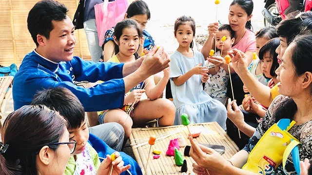 Nghệ nhân Đặng Văn Hậu đang hướng dẫn các em nhỏ nặn tò he.