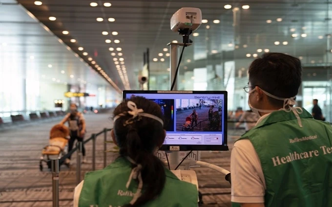 Nhân viên y tế túc trực bên máy đo thân nhiệt hành khách được đặt trong sân bay Changi, Singapore. (Ảnh: Bloomberg)
