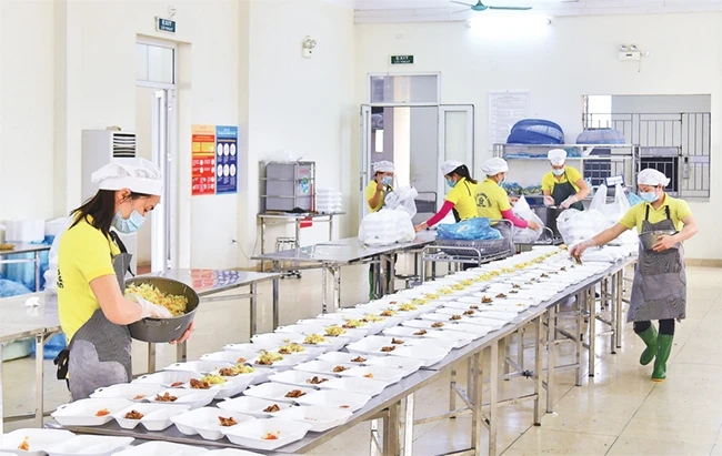 Các cán bộ nhà ăn Trường Quân sự Bộ Tư lệnh Thủ đô Hà Nội chuẩn bị các suất ăn cho công dân đang cách ly tại đây. Ảnh: MỸ HÀ